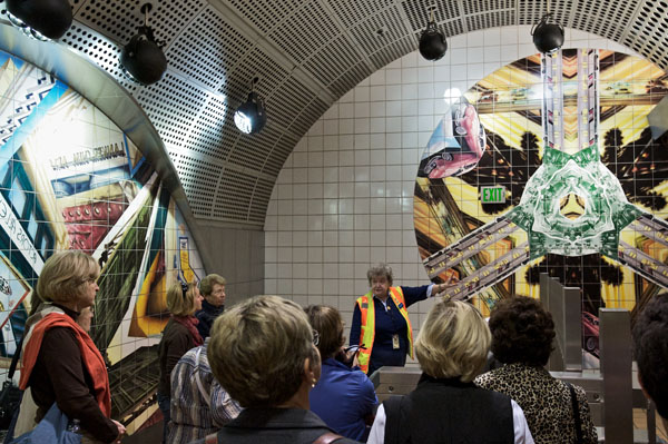 A Metro Art tour guide discusses the artwork at North Hollywood Station. The ceramic mural by Anne Marie Karlsen, called Kaleidoscope Dreams, depicts the dreams and aspirations of generations of San Fernando Valley immigrants and celebrates the Valley’s spirit and history.