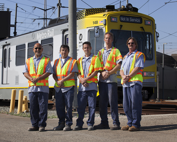 Detail of the new, bright yellow and white reflective markings and paint scheme rail car styling designed by Metro Creative Services. A test “mock up” was applied to an older car model by Lee Hetherington (right) in Blue Line Fleet Services and his capable team.