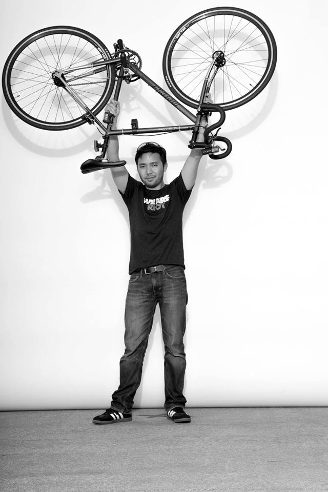 Alan holding his fixed gear bicycle over his head.