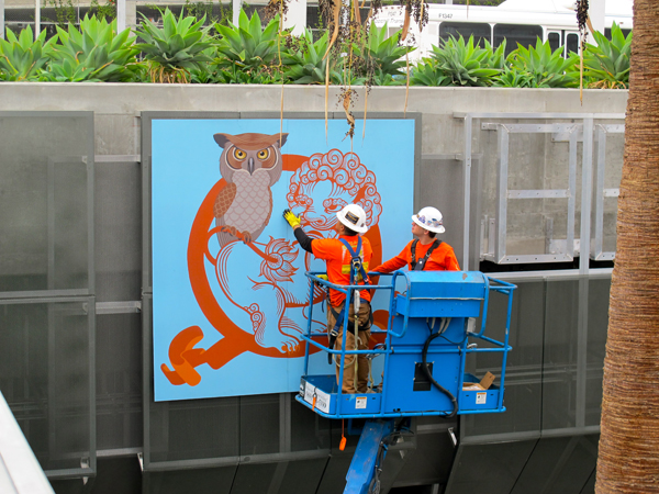 Phung Huynh's artwork being installed. Each artist created artwork in the medium of their choice, including drawing, painting and collage. This work was digitally captured in high-resolution digital files. The artwork was then translated onto 8’ x 8’ powder-coated aluminum panels, which can withstand the elements over the long-term, and are easy for Metro to maintain.