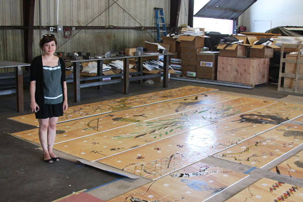 Shizu Saldamando inspecting her artwork panels are they were delivered by artwork fabricator Mayer of Munich to ensure that the colors of her original artwork are accurately reflected, and that the color is consistent among all of the panels.