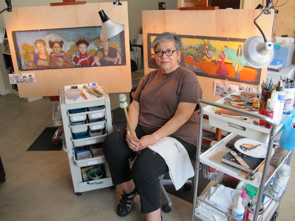 Artist Judithe Hernandez in her studio, with two of her original artworks for the Expo Line in the background.