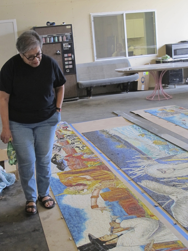 Judithe Hernandez inspecting her artwork panels after they were delivered by artwork fabricator Perdomo Studio to ensure that the colors of her original artwork are accurately reflected, and that the color is consistent among all 24 of the panels.