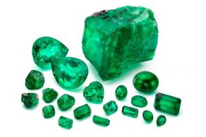 Loose emeralds from Marcial de Gomar Collection. Nine Pillars of Andes rough emeralds shown at the bottom left-hand corner of the image