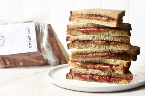 Plate of stacked PBJ sandwiches, open bag of bread in background