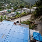 A home with a temporary roof in a sheltered valley of hilly Jayuya.