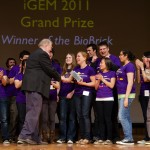Liz Stanley, a senior majoring in microbiology, accepts the brick trophy on a Boston stage Nov. 7 for the iGEM team's "World Champion" win in genetic engineering. The brick is a symbol of the molecular components that are used in synthetic biology.