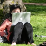 A student looks at a computer on the UW Quad.