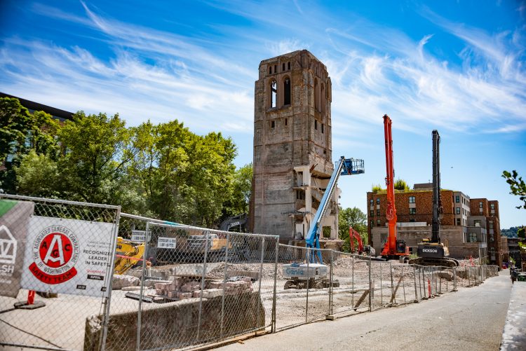 An old church tower stands on a construction site with a crane