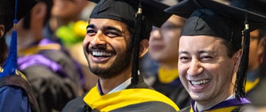 two men in graduation caps and gowns during crowded GIX graduation ceremony 2018