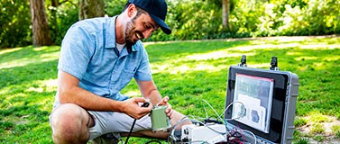 A researcher learns to set up a seismometer to measure ground motion.