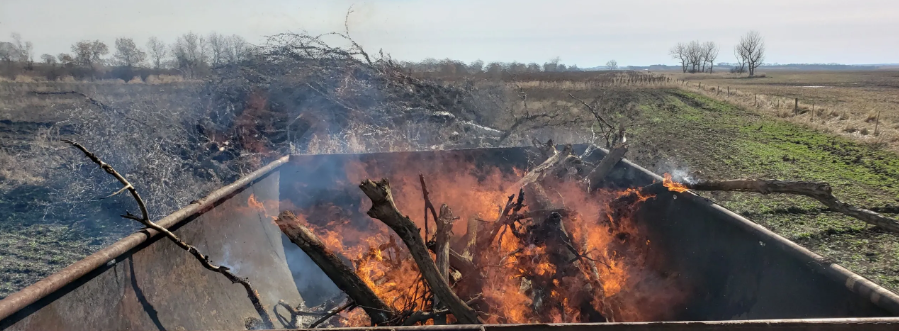 Waste wood burns in oil tank repurposed as a kiln.