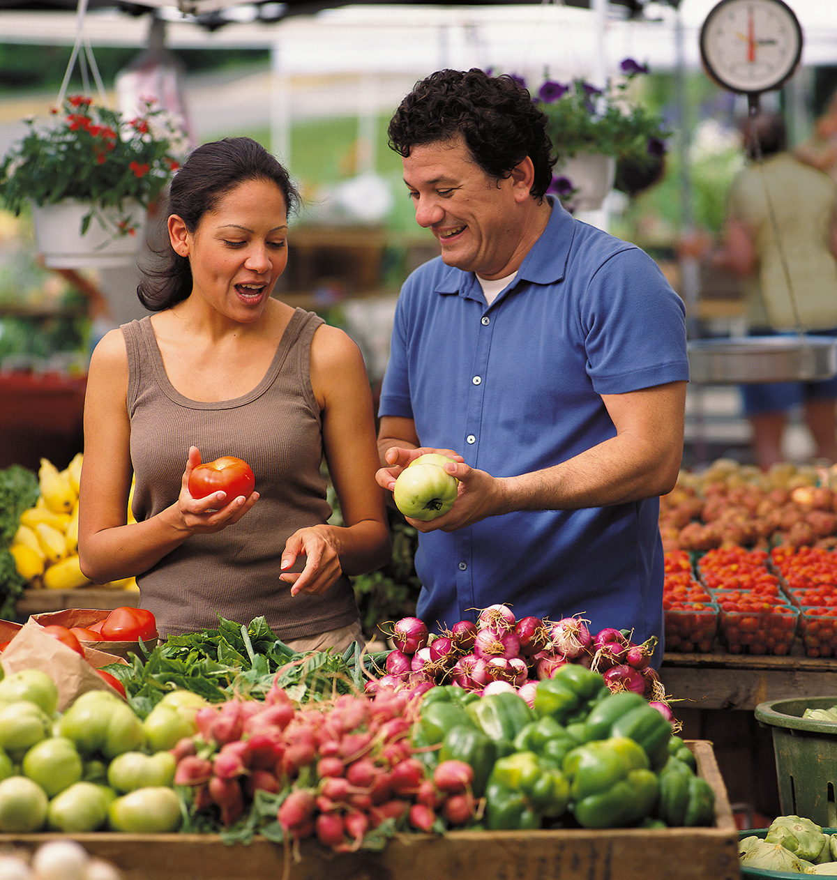 Man and woman holding vegetables in a farmers market