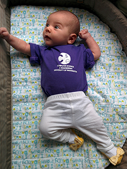 Baby in purple CSE t-shirt and yellow bow-tie shoes
