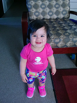 Smiling toddler in pink CSE t-shirt and matching sneakers
