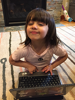 Little girl in CSE t-shirt playing with a laptop computer