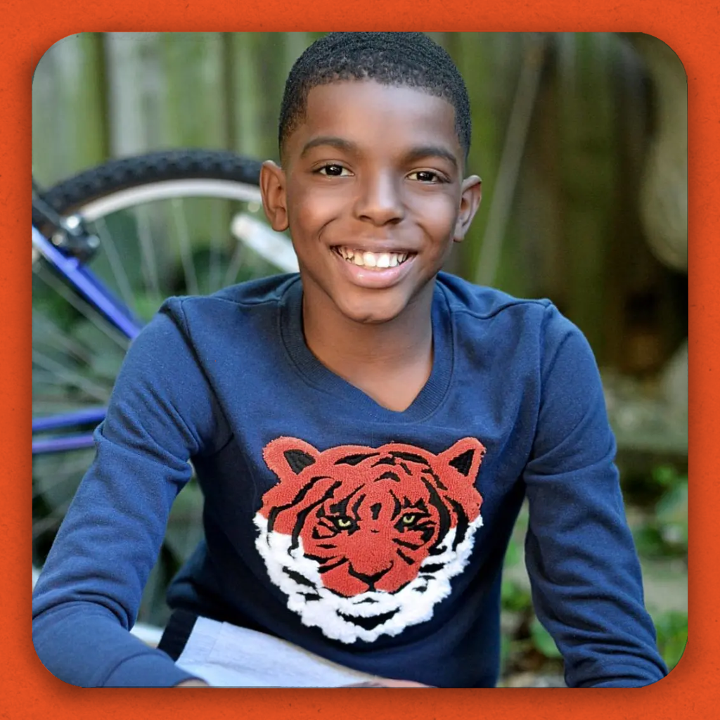 A smiling black boy in a tiger shirt