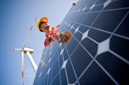 Image of a technician in between wind and solar technologies. In the background you can see Wind Turbines. Two different technologies to produce energy in a responsible and sustainable way.