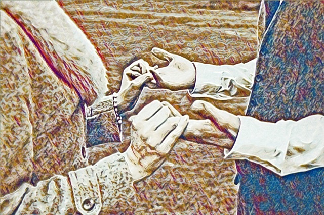 Close up photo of a bride and groom holding hands during a wedding ceremony. 