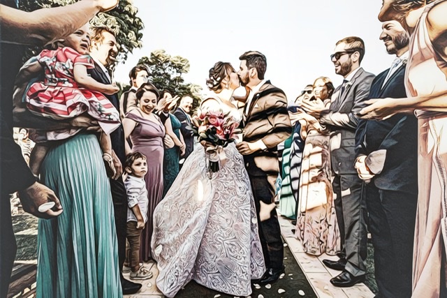 Newlyweds kiss, surrounded by friends and family members after their wedding ceremony.