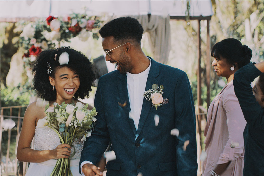 bride and groom smile after the ceremony, surrounded by friends and family