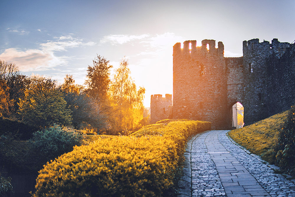 The sun rises against a medieval era castle, a romantic themed image in honor of this medieval wedding ceremony script 