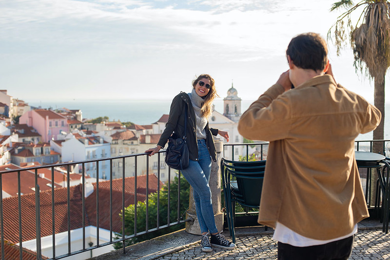 image is a photograph of a young couple on vacation, taking photos in front of famous buildings and views