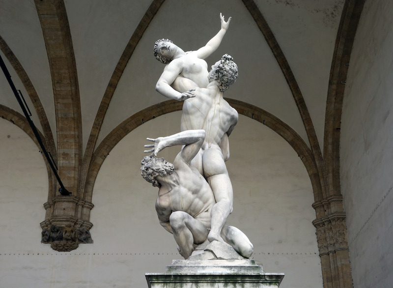 A marble sculpture of two nude men carrying off a nude woman as she struggles to get away.  The sculpture gives the sense of urgency and movement, the woman's mouth is open in a gasp, and her head falls back as she reaches out toward the sky in struggle. Below her, one man grasps her, holding her down by the torso and sides, and other man crouches on the ground, twisting up to watch, grasping her legs with an expression of upset or anguish. 