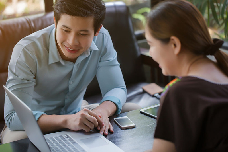 A smiling man and woman look at a laptop screen together