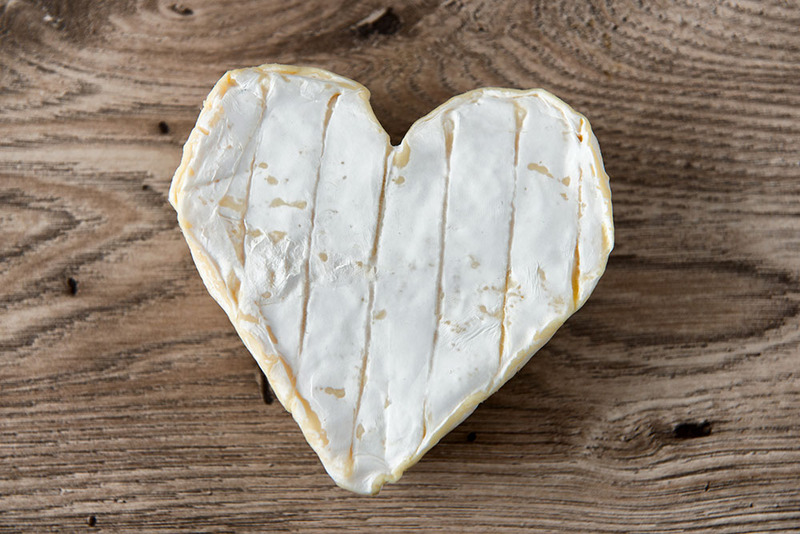 cheese in the shape of a heart sitting on a wooden table