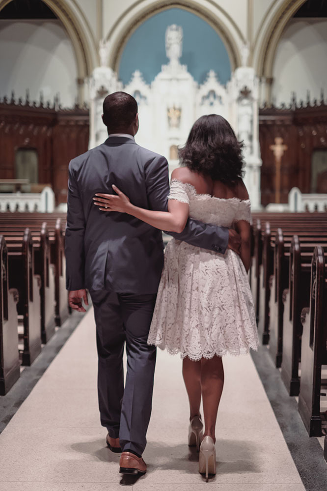 A young black couple walk down the wedding aisle together