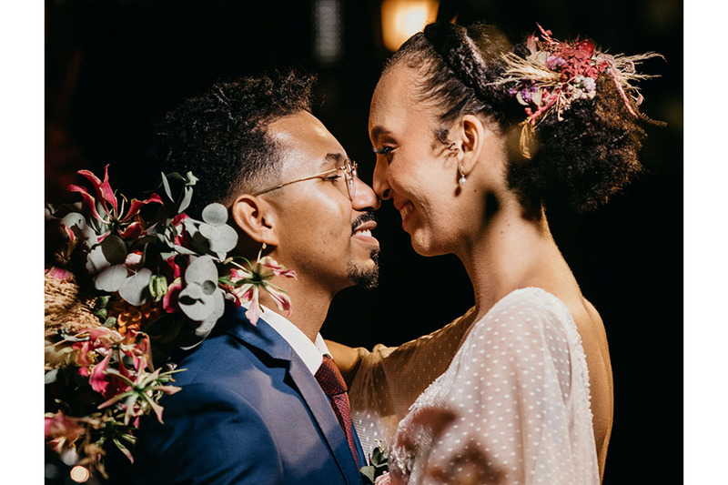 A young couple with flowers kiss on the wedding day, this is a photo of them from the profile with their noses touching as they smile