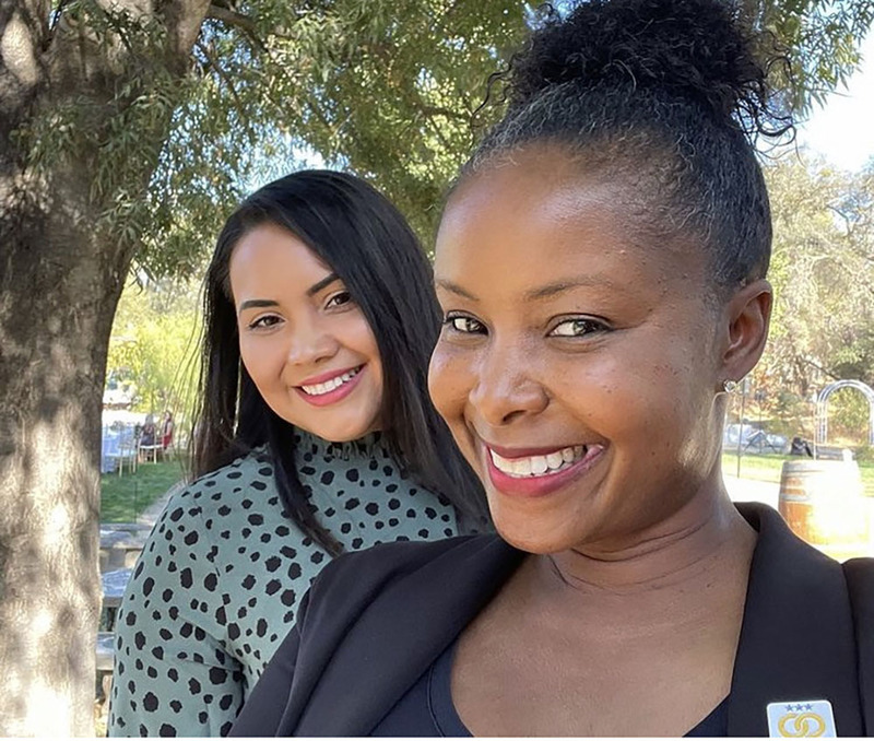 Raquel and her friend Erika take a selfie while smiling outside 