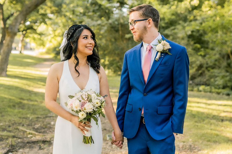 A happy couple smiling outdoors during their wedding ceremony