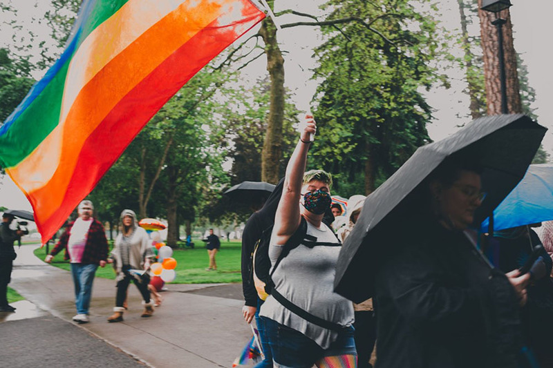 A person holds up a large rainbow flag at the Coeur d'Alene Pride in the Park event 