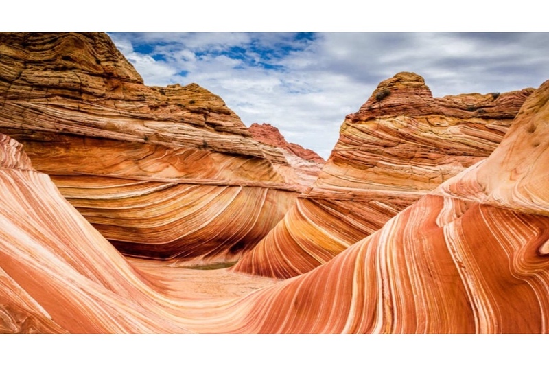 Photo of the orange and red striated rocks that form The Wave in Arizona, a breathtaking natural formation that resembles Mars & a Martian landscape