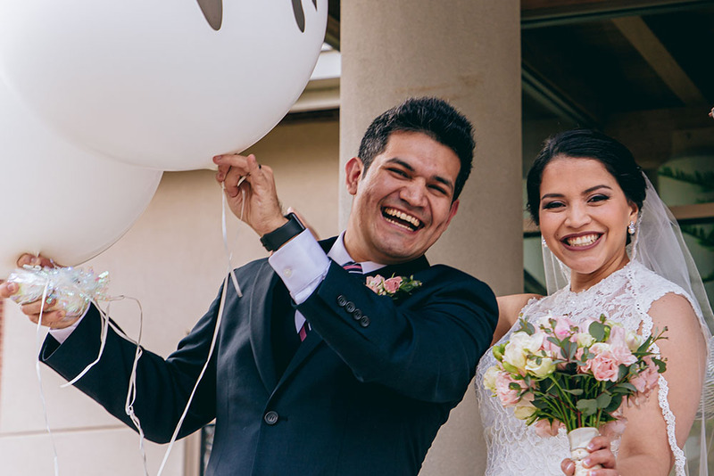 A happy Latino groom and bride smile and laugh on their wedding day following the marriage ceremony 