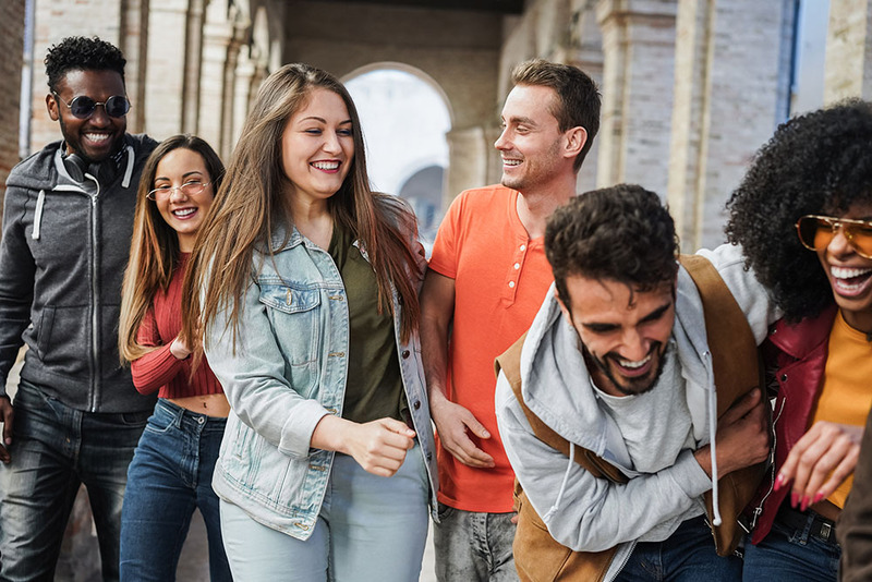 A group of friends laugh and smile together while walking happily outdoors