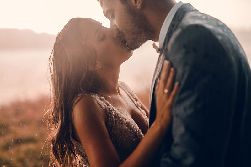 A young couple kiss at sunset on the wedding day