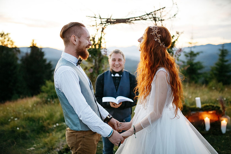 Young couple holds hands during their wedding ceremony outdoors