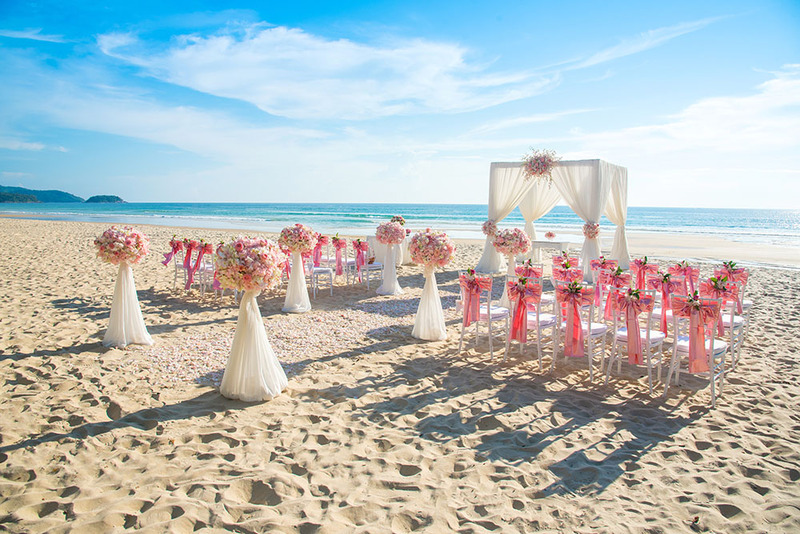 Beautiful Florida beach wedding with flowers and chairs set out in the sand, with the ocean and blue sky in the background