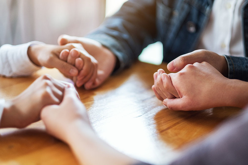 Friends holding hands while praying