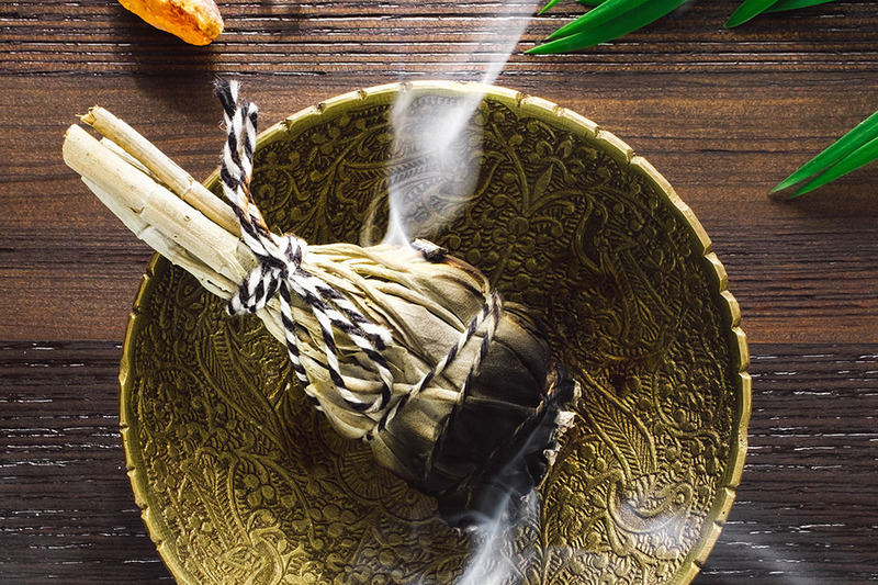 Sage burning in a ceremonial bowl with crystals near by, during a smudging ceremony