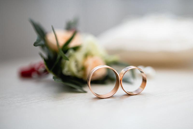 Close up photo of two wedding rings  and wedding flowers