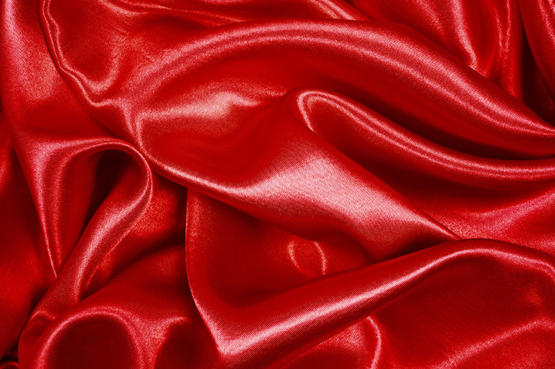 A close up image of red satin, with creases and curves and shine