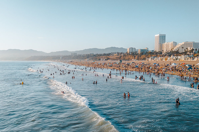 Photo of Santa Monica, California, taken from the water, with tall skyscrapers and lots of people enjoying the ocean water and beach