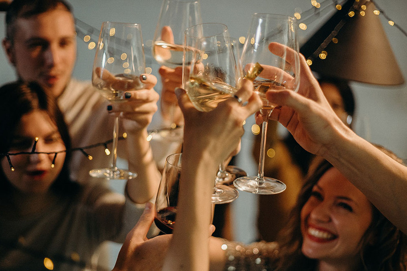 A close up photo of friends holding up their wine glasses to make a toast in celebration of a wedding