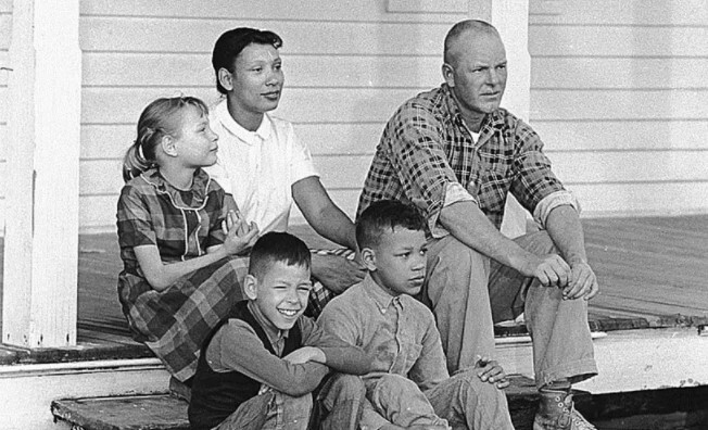 Historic black and white photograph of the Loving family, taken with their children outside on the porch