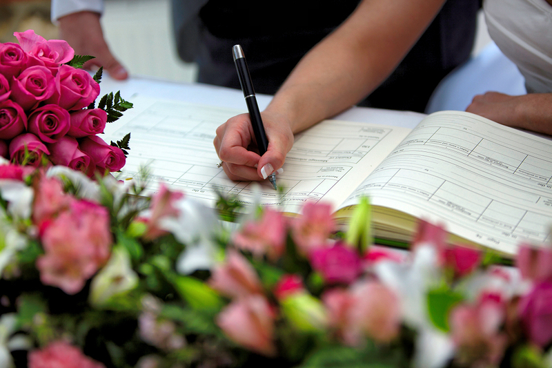 Close up photo as a bride signs her marriage license registry book after the wedding ceremony