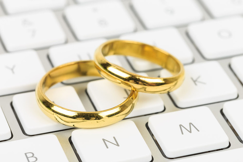 Close up photo of gold wedding rings resting on a laptop keyboard